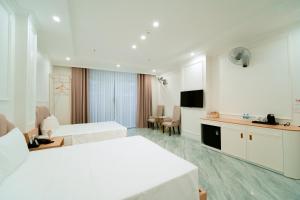 a white hotel room with two beds and a tv at Nhật Tân Hotel Triển Lãm VEC - Đông Anh in Dong Anh