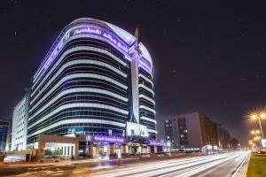 a large building with purple lights on it at night at Grand Excelsior Hotel - Bur Dubai in Dubai
