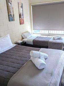 a hotel room with two beds with towels on them at The Swiss Motel in Cooma