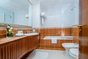 a bathroom with a sink and a toilet and a mirror at Grand Excelsior Hotel - Bur Dubai in Dubai