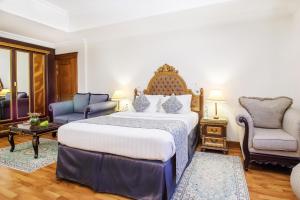 a bedroom with a king sized bed and two chairs at Grand Excelsior Hotel - Bur Dubai in Dubai