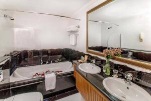a bathroom with two sinks and a tub and a mirror at Grand Excelsior Hotel - Bur Dubai in Dubai