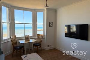 a dining room with a table and chairs and windows at Beach Lookout Direct Access to Viking Bay Sleeps 4 in Kent