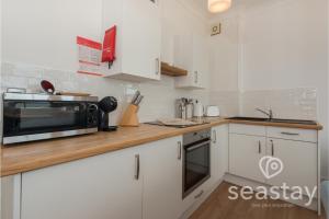 a kitchen with white cabinets and a microwave at Beach Lookout Direct Access to Viking Bay Sleeps 4 in Kent