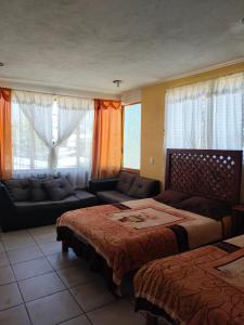 a bedroom with two beds and a couch and windows at DEPA3 4 personas SanFco in Zacatlán