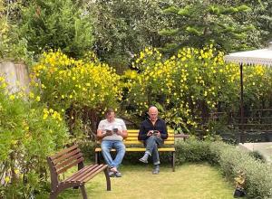 two men sitting on a bench in a garden at Pakha Dhim Heritage Homestay in Namchi