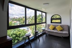 a living room with a couch and large windows at The Node Homestay & Apartment in Xuan An