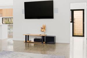 a living room with a tv on a white wall at Tea Tree Poolside Escape in Inverloch