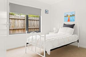 a white bedroom with a bed and a window at Tea Tree Poolside Escape in Inverloch +15 photos