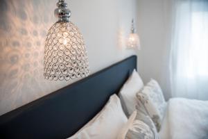 a chandelier hanging over a bed with white pillows at M-Loft merangardenvilla in Merano