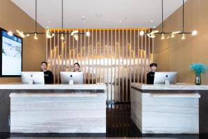 three people sitting at a counter with their laptops at 库尔勒孔雀河景观带滨河西路亚朵酒店 in Korla