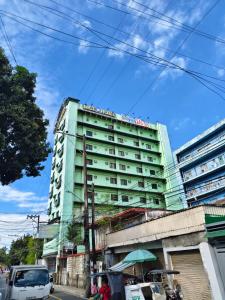 a green building with a sign on top of it at Nice Hotel Aurora Cubao in Manila