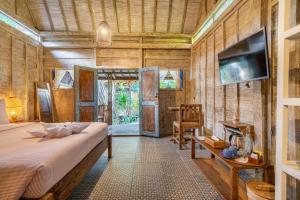 a bedroom with a bed and a tv in a room at Ortigia Tropical Lodge in Gili Trawangan