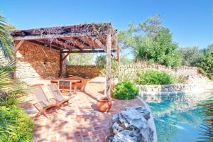 a swimming pool with two chairs and a pergola at Casinha Antiga in Boliqueime