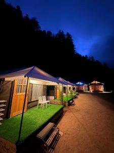 a group of tents with grass and chairs on a field at The Pravaas Resort in Barot 