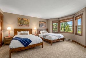 two beds in a room with two windows at Duck Inn Lodge in Whitefish