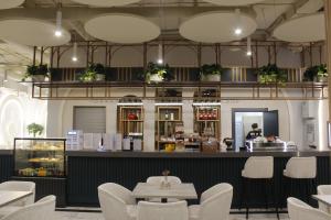a restaurant with a bar with white chairs and a counter at ADD Hotel Almaty in Almaty
