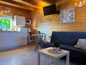 a living room with a blue couch and a kitchen at Domki letniskowe Nadia z podgrzewanym basenem in Władysławowo