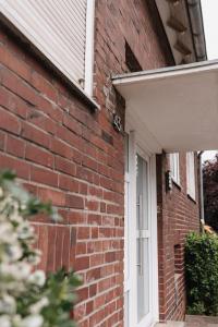 a brick house with a white door and a brick wall at Bright Nest in Drensteinfurt