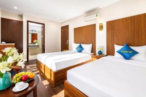 a hotel room with two beds and a table at Sea Front Apartment & Spa Da Nang in Danang