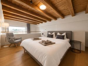 a bedroom with a large white bed and a chair at LAKE-LOFT APARTMENT's direkt im Hafen in Romanshorn
