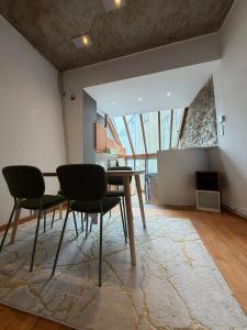 a dining room with a table and chairs on a rug at Le Studio Central in Huy