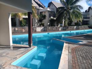 a swimming pool with blue water in front of a house at Well located and Comfortable Villa in Grand-Baie