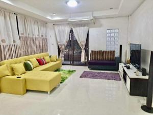 a living room with a yellow couch and a tv at Pani House Hatyai 6 in Hat Yai