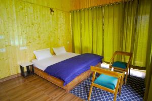 a small bedroom with a bed and a chair at Kabila King Resort in Chakrāta +41 photos