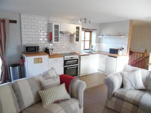 eine Küche mit 2 Sofas und eine Küche mit einem Herd in der Unterkunft Primrose Cottage in North Petherwin