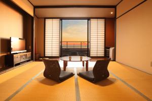 a living room with a table and chairs and a large window at ゆうみ in Kyonan