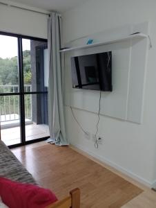a living room with a tv on the wall at Apartamento próximo ao Aeroporto e Curitiba in São José dos Pinhais
