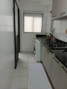 a white kitchen with a stove and a window at Apartamento próximo ao Aeroporto e Curitiba in São José dos Pinhais