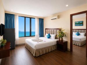 a hotel room with two beds and a large window at Sea Front Apartment & Spa Da Nang in Danang