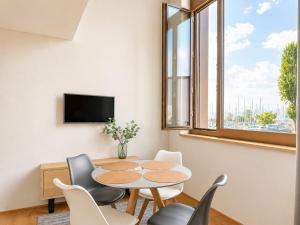 a dining room with a table and chairs and a tv at LAKE-SIDE Säntisblick in Romanshorn