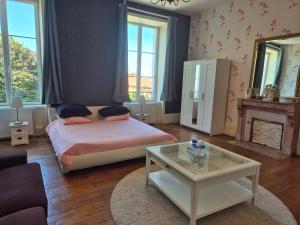 a bedroom with a bed and a table and a fireplace at Domaine de Savignac in Chabanais +37 photos