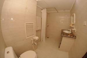 a white bathroom with a toilet and a sink at Mehran Hotel Karachi in Karachi
