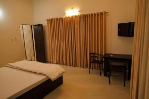 a bedroom with a bed and a desk and a table at The Calm County Homestay in Mānantoddy