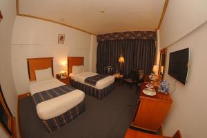 a hotel room with two beds and a television at Mehran Hotel Karachi in Karachi