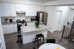 a kitchen with white cabinets and a granite counter top at Hiltons Villa in Brampton