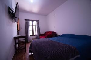 a bedroom with a bed and a chair and a window at TIlcara Rooms in Tilcara +7 photos