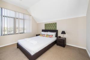 a bedroom with a large bed and a window at Serenity Townhouse in Mandurah