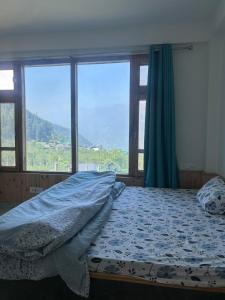 a bedroom with a bed with a large window at Nashala View Homestay in Nagar +4 photos