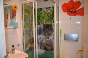 a shower in a bathroom with a painting of a waterfall at Ferieneinrichtungen Haus am Stein bei B in Königstein an der Elbe +48 photos