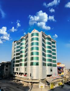 a tall white building with green windows at Fort Continental Hotel in Peshawar
