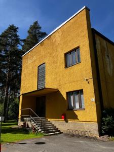 a large yellow building with stairs and windows at Aliupseerikerho in Kauhava