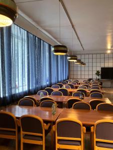 a conference room with tables and chairs and windows at Aliupseerikerho in Kauhava