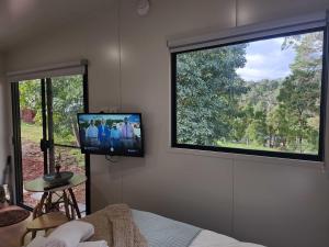 a room with a tv and a large window at Rosebank Tiny House in Healesville