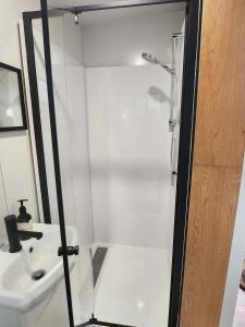 a white bathroom with a shower and a sink at Rosebank Tiny House in Healesville +6 photos