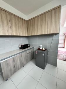 a kitchen with wooden cabinets and a small refrigerator at Exclusive Changlun Room in Bukit Kayu Hitam